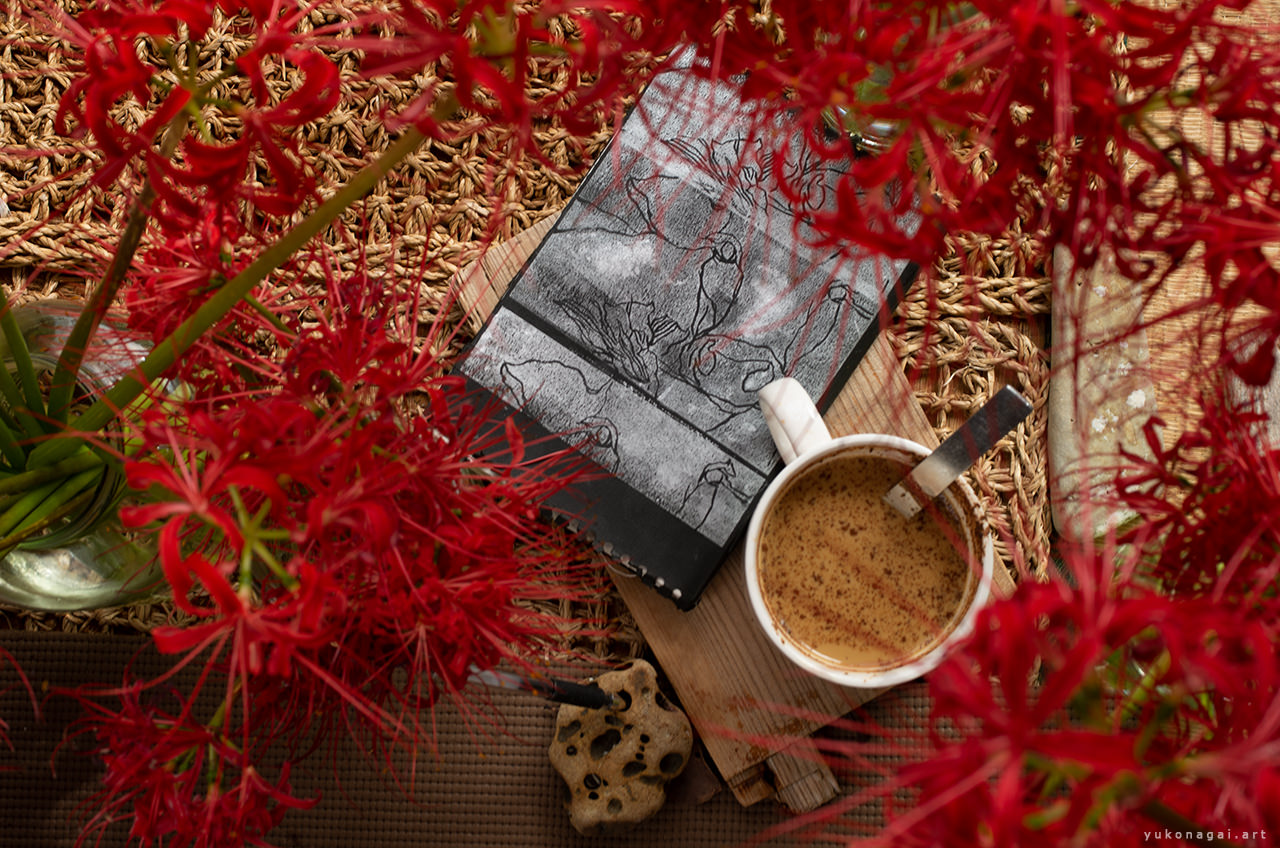 An art print journal book, a cup of tea, spider lily bouquets.